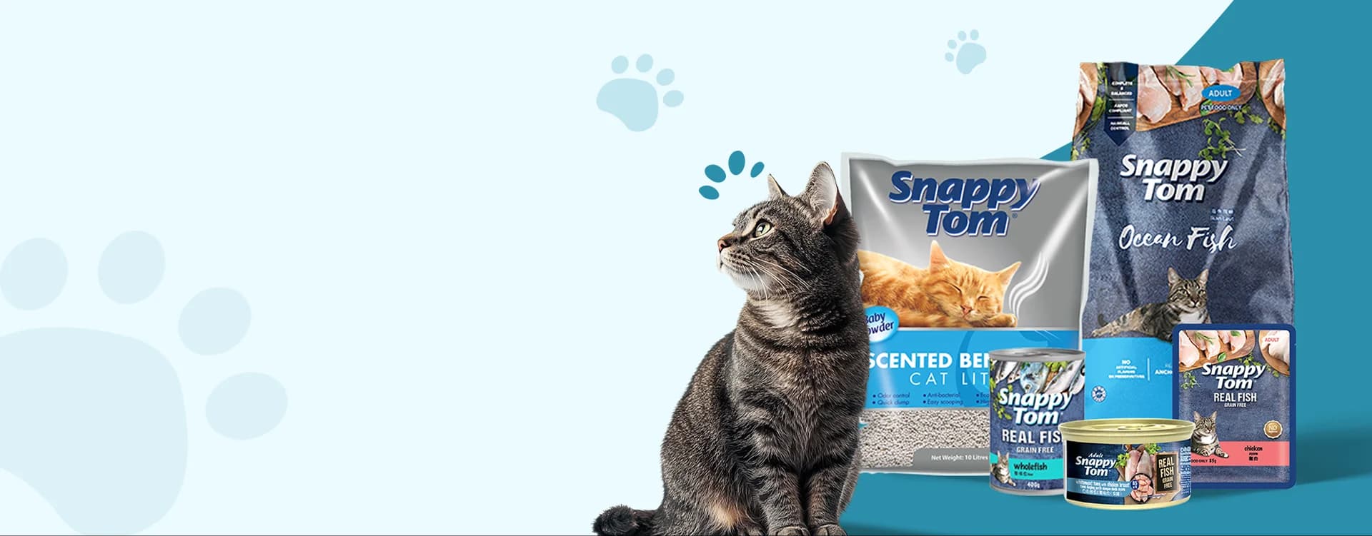 A tabby cat beside the Snappy Tom range of dry food, wet food, pouches and cat litter